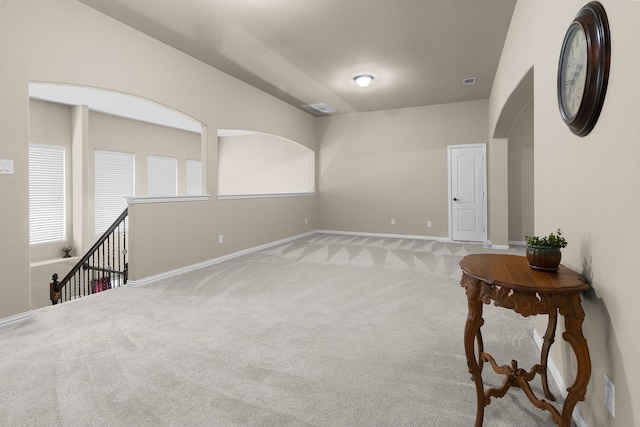 unfurnished room with arched walkways, baseboards, and carpet