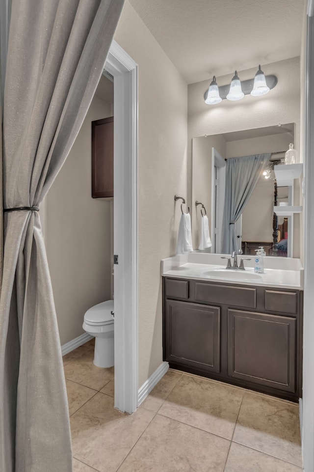 bathroom featuring vanity, baseboards, tile patterned flooring, and toilet