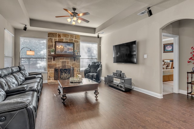 living area with ceiling fan, arched walkways, a fireplace, wood finished floors, and baseboards