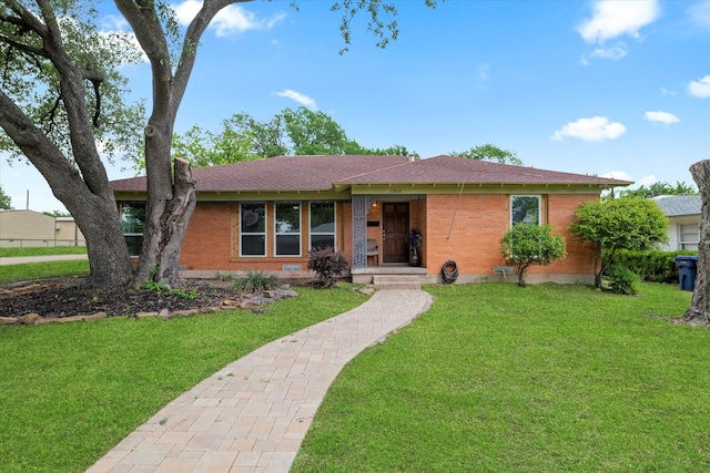 ranch-style house with brick siding, a shingled roof, and a front lawn