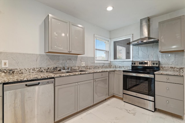 kitchen featuring gray cabinets, a sink, marble finish floor, stainless steel appliances, and wall chimney exhaust hood