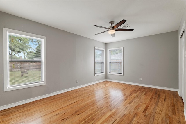 empty room with baseboards, a wealth of natural light, and light wood finished floors