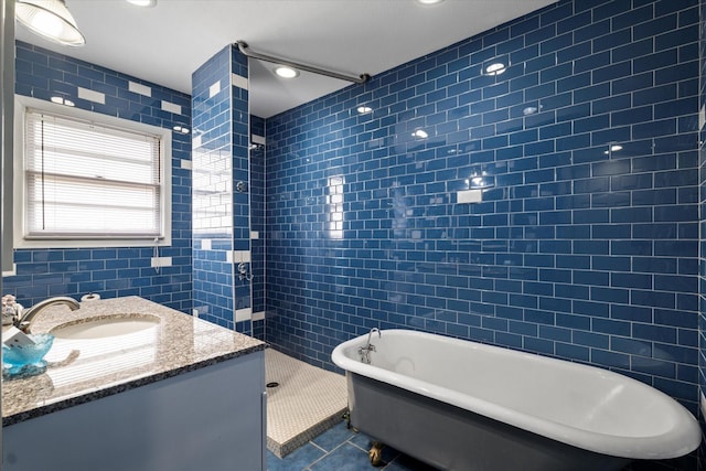 bathroom with walk in shower, vanity, tile patterned floors, tile walls, and a soaking tub