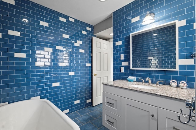 bathroom with a freestanding bath, tile patterned flooring, vanity, recessed lighting, and tile walls