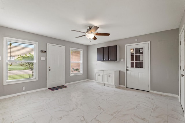 foyer with baseboards, marble finish floor, ceiling fan, and a healthy amount of sunlight