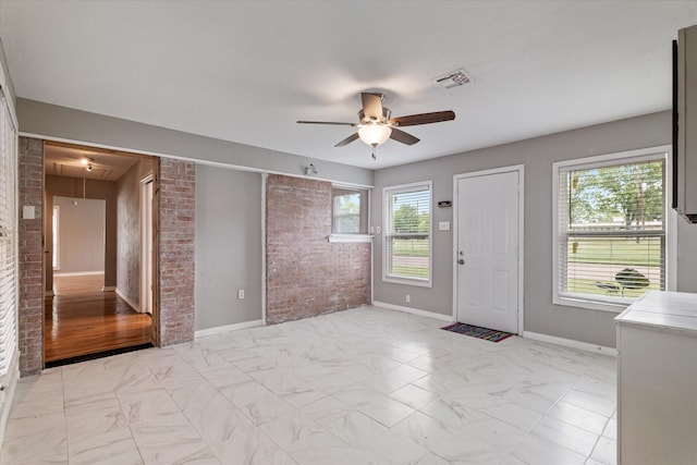 foyer featuring visible vents, marble finish floor, ceiling fan, and brick wall