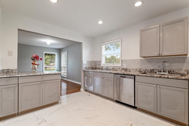 kitchen with light stone countertops, a sink, marble finish floor, stainless steel dishwasher, and gray cabinetry