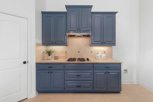 bar with tasteful backsplash, light tile patterned floors, baseboards, stainless steel gas stovetop, and under cabinet range hood