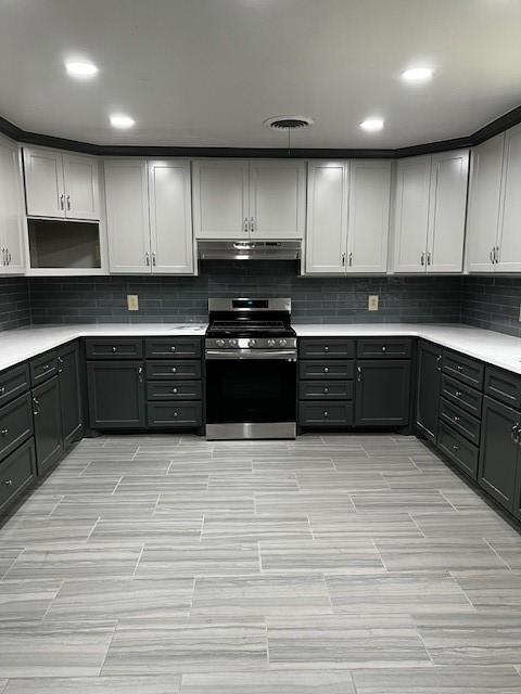kitchen featuring wood tiled floor, gray cabinets, gas range, tasteful backsplash, and under cabinet range hood