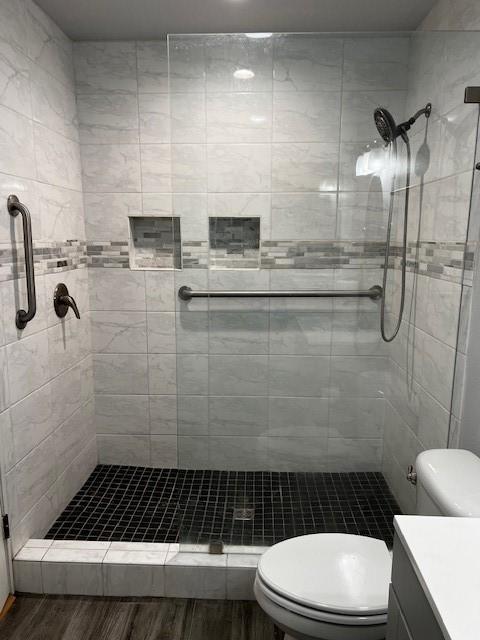 full bathroom featuring vanity, wood finished floors, toilet, and a shower stall