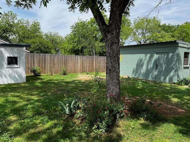 view of yard with an outdoor structure, fence, and a storage unit