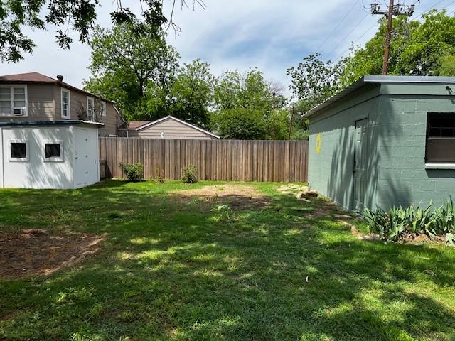view of yard with an outdoor structure, fence, and a shed