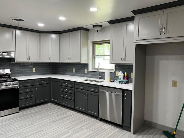kitchen featuring a sink, appliances with stainless steel finishes, exhaust hood, and gray cabinetry
