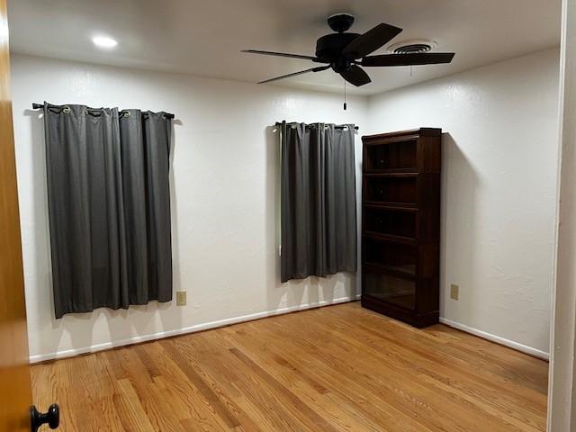 empty room featuring baseboards, ceiling fan, and wood finished floors