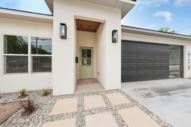 928 College St, Sulphur Springs, TX 75482 - view of exterior entry with an attached garage, stucco siding, and driveway