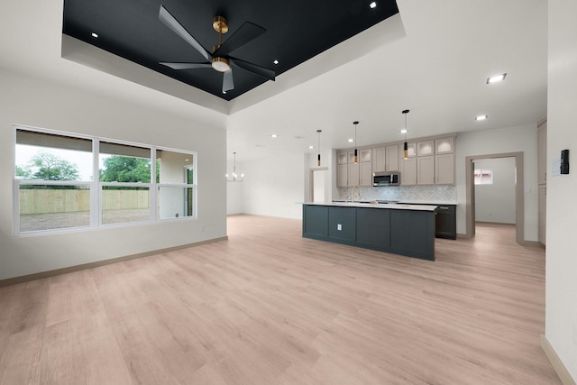 928 College St, Sulphur Springs, TX 75482 - kitchen with open floor plan, a raised ceiling, stainless steel microwave, tasteful backsplash, and light wood-style flooring