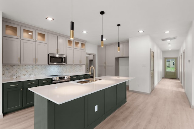 928 College St, Sulphur Springs, TX 75482 - kitchen featuring visible vents, decorative backsplash, a sink, light wood-style flooring, and appliances with stainless steel finishes