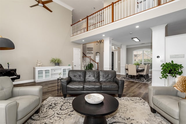 living area featuring baseboards, a high ceiling, ornamental molding, and wood finished floors