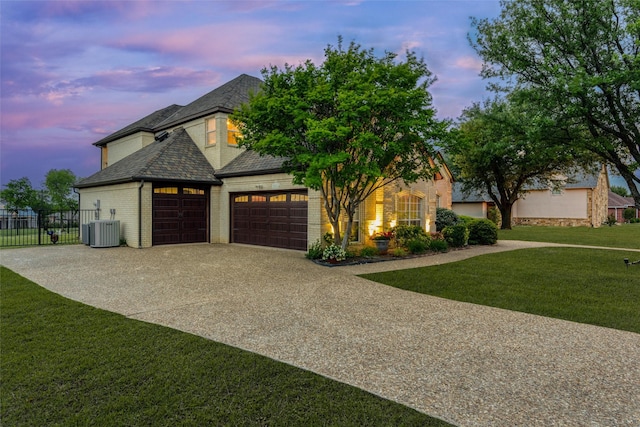 view of front facade with central AC unit, a garage, brick siding, fence, and a front lawn