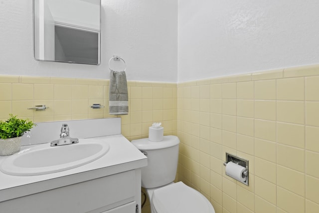 bathroom with vanity, a wainscoted wall, toilet, and tile walls