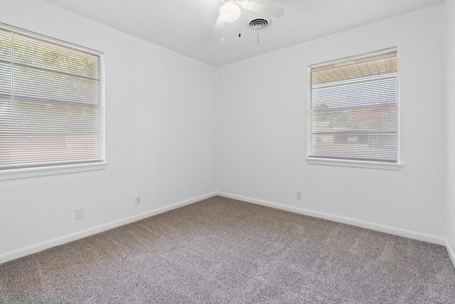 spare room with visible vents, a healthy amount of sunlight, baseboards, a ceiling fan, and carpet