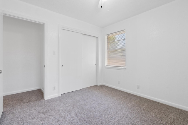 unfurnished bedroom with a closet, baseboards, and carpet flooring