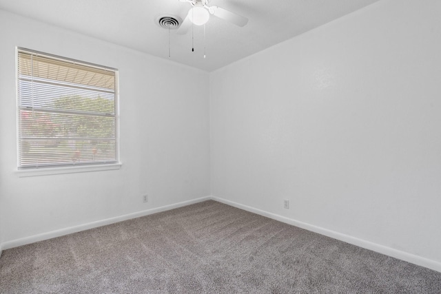 empty room with carpet floors, baseboards, a ceiling fan, and visible vents