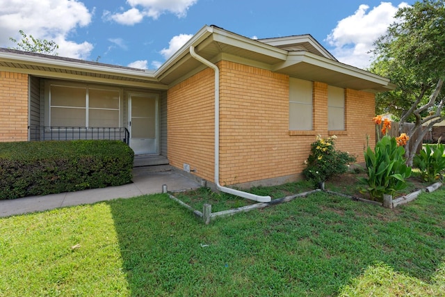 view of side of home with a lawn, fence, and brick siding