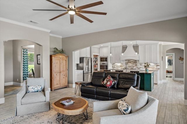 living room featuring visible vents, baseboards, ceiling fan, light wood-type flooring, and arched walkways