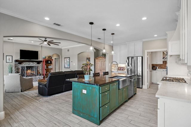 kitchen featuring ceiling fan, arched walkways, stainless steel appliances, visible vents, and green cabinets