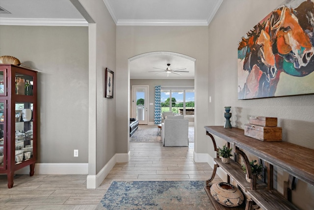 entrance foyer featuring arched walkways, a ceiling fan, baseboards, wood tiled floor, and ornamental molding