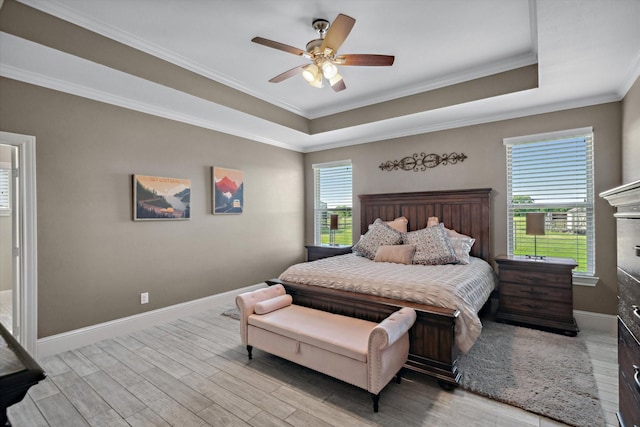 bedroom featuring baseboards, a tray ceiling, ornamental molding, and wood finished floors