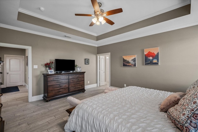 bedroom with crown molding, a raised ceiling, and light wood-style flooring