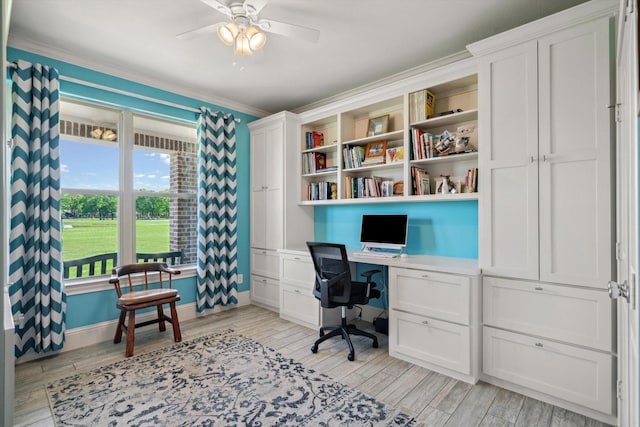 home office with crown molding, ceiling fan, built in desk, and light wood-style flooring