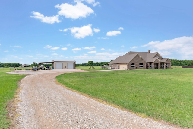 view of front facade featuring dirt driveway, a garage, an outbuilding, and a front lawn