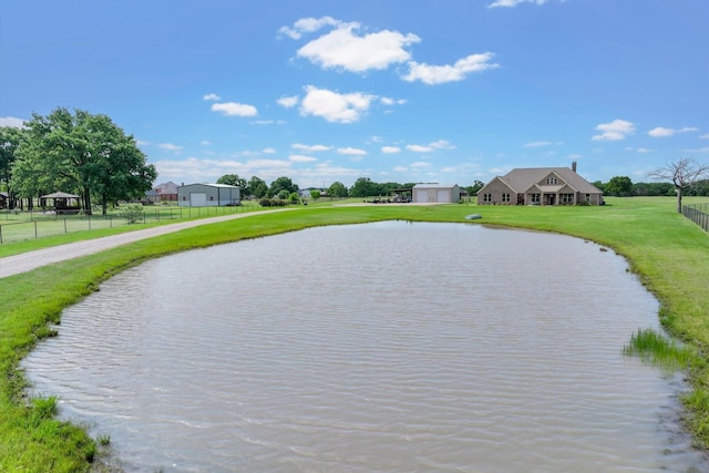 view of property's community with fence, a water view, a lawn, and driveway