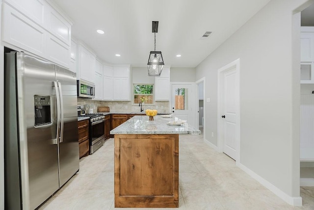 3600 Howard St, Fort Worth, TX 76119 - kitchen with appliances with stainless steel finishes, tasteful backsplash, light stone countertops, white cabinets, and a kitchen island
