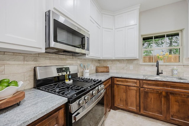 3600 Howard St, Fort Worth, TX 76119 - kitchen featuring appliances with stainless steel finishes, a sink, light stone countertops, white cabinets, and backsplash