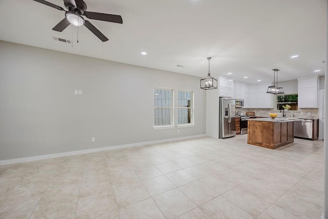 3600 Howard St, Fort Worth, TX 76119 - kitchen featuring stainless steel appliances, open floor plan, a center island, decorative backsplash, and white cabinets