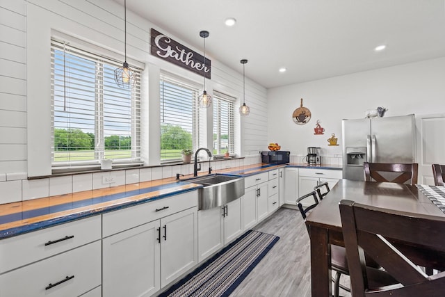 kitchen with white cabinets, decorative light fixtures, a sink, and stainless steel fridge with ice dispenser