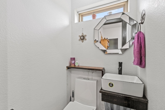 bathroom featuring a textured wall and toilet
