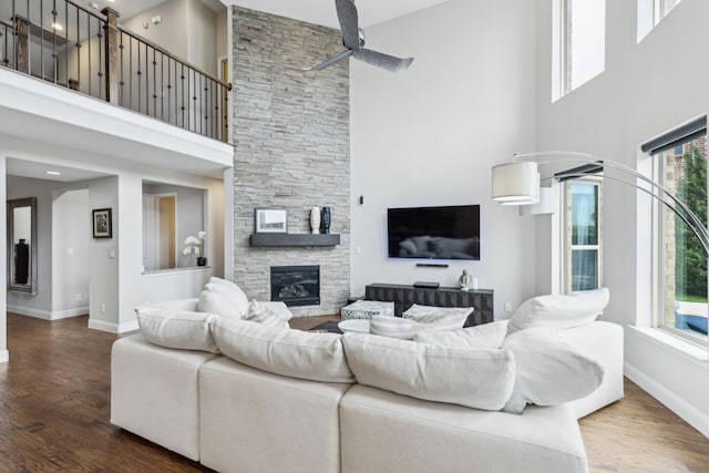 living room featuring a high ceiling, baseboards, and wood finished floors