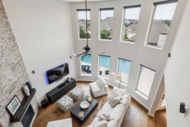 living area with baseboards, wood finished floors, and a towering ceiling