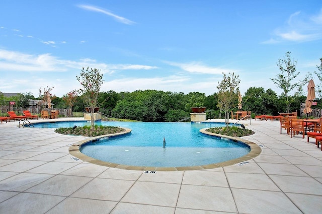 community pool with a patio and fence