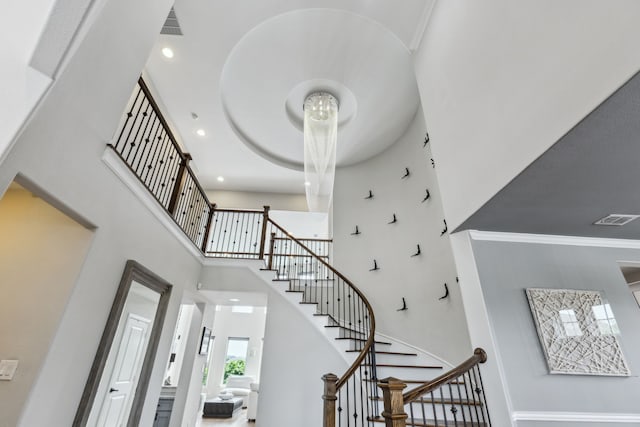 entrance foyer with stairway, crown molding, a high ceiling, and visible vents