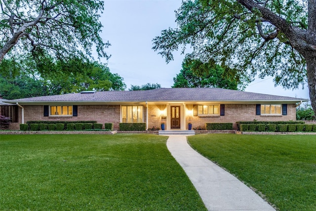 ranch-style home featuring a front lawn and brick siding