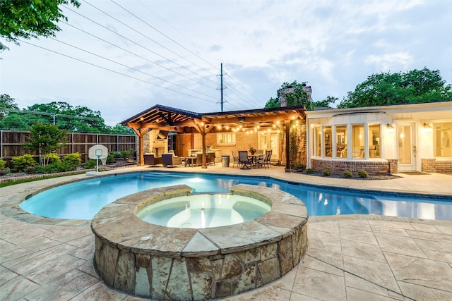 view of swimming pool with a patio, a pool with connected hot tub, fence, and outdoor dining space