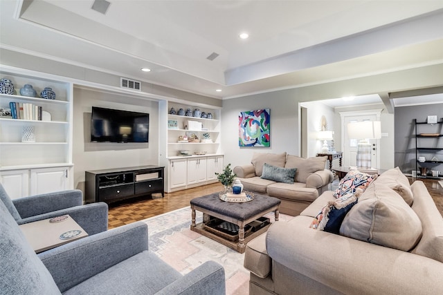 living room with ornamental molding, a tray ceiling, and visible vents