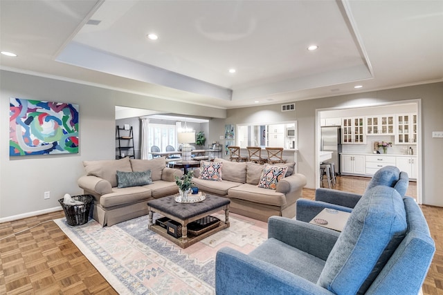 living area with visible vents, recessed lighting, a raised ceiling, and baseboards