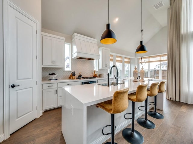 kitchen featuring a sink, high vaulted ceiling, custom range hood, backsplash, and visible vents